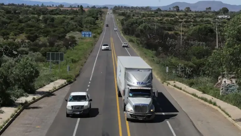 Un tractocamión circula por una carretera de Guanajuato mientras patrullas realizan labores de vigilancia