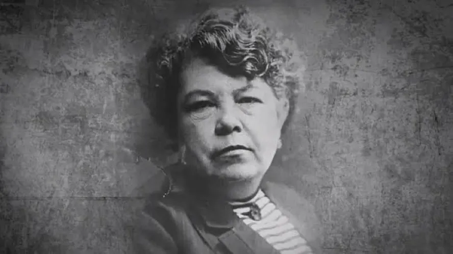 Médica con bata blanca junto a un libro antiguo de medicina, en representación del legado de Consuelo Gutiérrez García en Guanajuato.